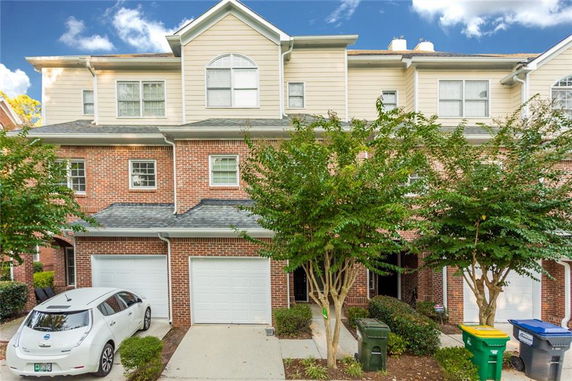 Front view of a townhouse with a brick exterior and attached garage.