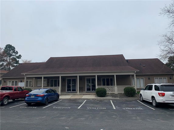 Front view of a single-story building with a porch and parking area.