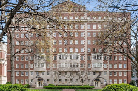 Front view of a multi-story brick building with decorative balconies and arched entrance.