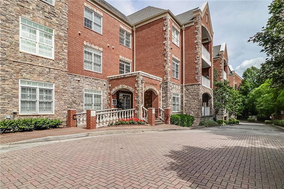 Front view of a three-story brick and stone building with arched entrance.