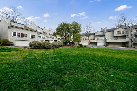Front view of a row of multi-story townhouses with garages.