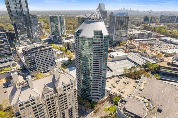 Front view of a modern, tall skyscraper surrounded by other high-rise buildings in a cityscape.
