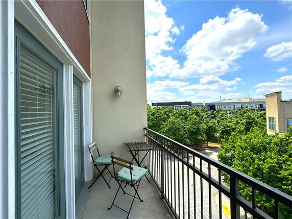 View from a balcony overlooking a courtyard with surrounding buildings and trees.