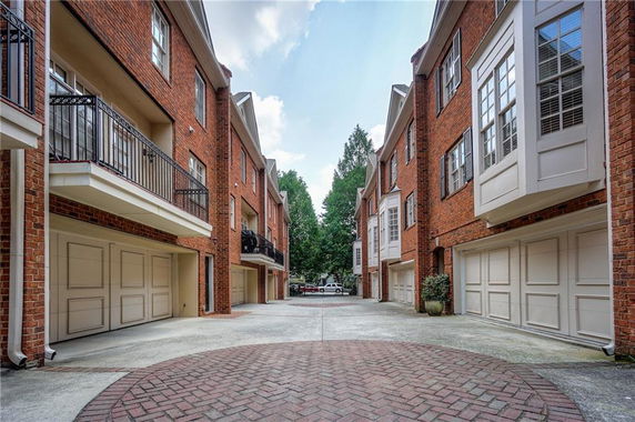 Outdoor parking area with brick residential buildings and garages.