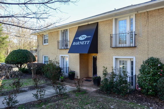 Front view of a two-story brick apartment building with a central entrance awning.
