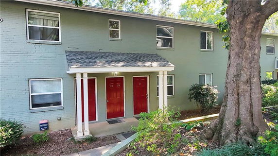 Front view of a two-story building with three red doors and a small porch.