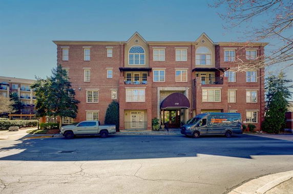 Front view of a four-story brick apartment building with arched windows and a central entrance.