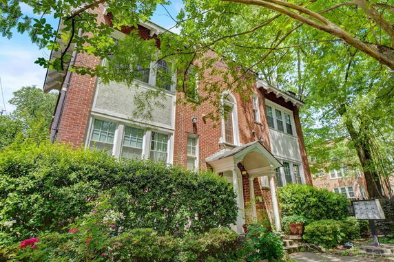 Front view of a two-story brick house with white trim and an arched entrance.