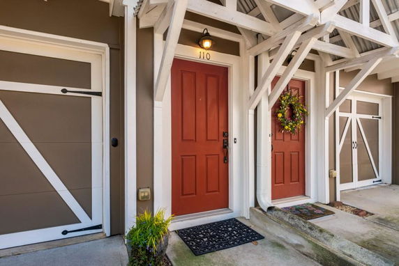Front view of a house entrance with a red door and decorative wreath.