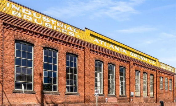 Front view of a brick industrial building with multiple large windows.