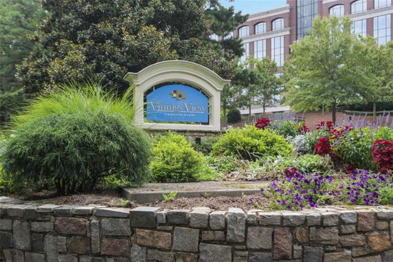 Front view of a multi-story condominium building with a landscaped entrance sign.
