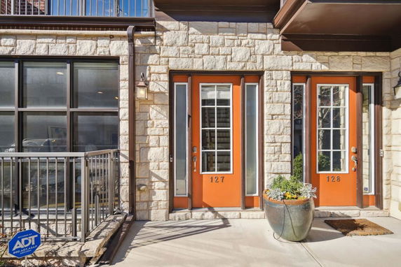 Front view of a building with two orange doors labeled 127 and 128 and stone exterior walls.