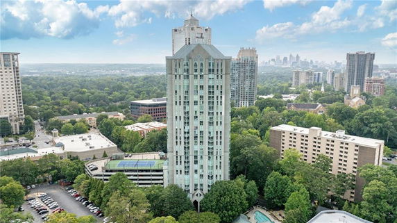 Aerial view of a high-rise building surrounded by trees and other buildings in an urban area.