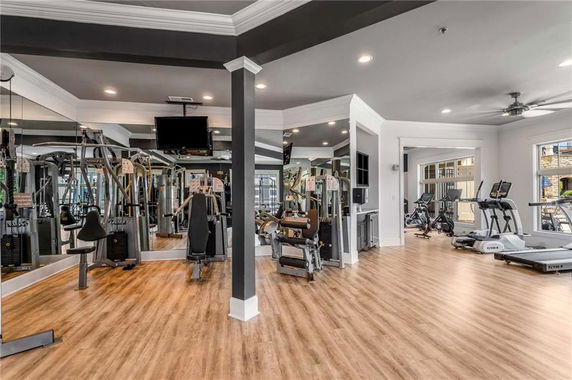 Interior view of a gym with various exercise equipment and mirrored walls.