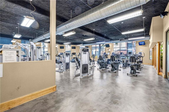 Interior view of a gym area with exercise equipment, including stationary bikes and weight machines.