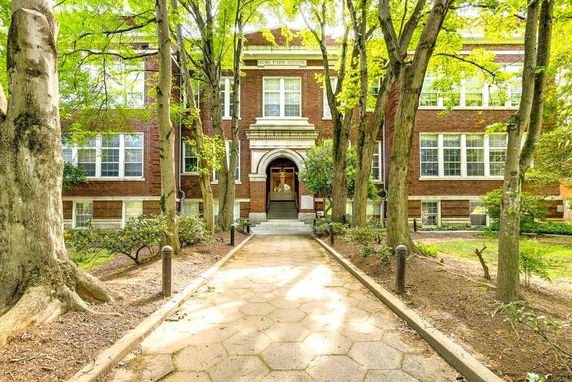 Front view of a multi-story brick building with large windows and a central entrance.