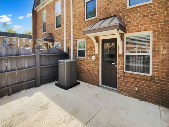 Back view of a brick house with a small porch and air conditioning unit.