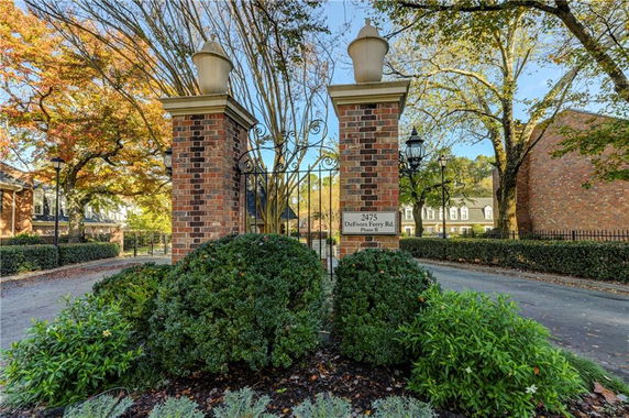 Front view of a gated entrance with brick pillars and ornate metal gate.
