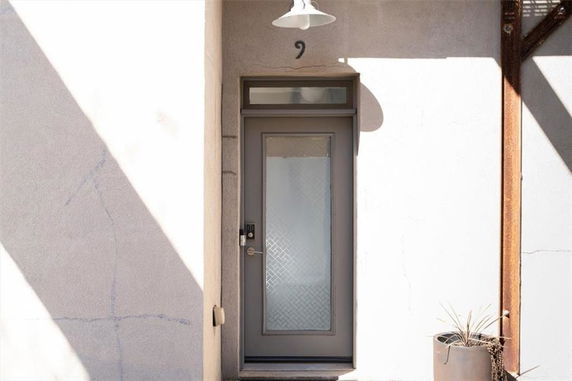 Front view of a door entrance on a plain exterior wall with a light fixture above.