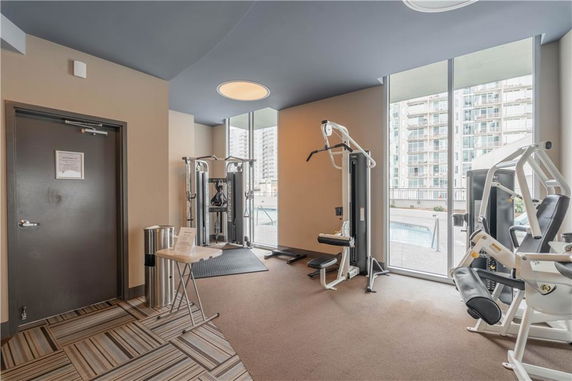 Indoor gym with workout equipment and large windows.