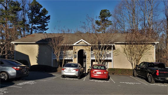 Front view of a two-story building with a small parking area.