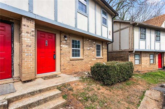 Front view of a two-story building with red doors and brick facade.