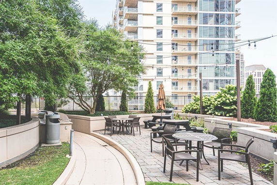 Outdoor patio area with tables and chairs in front of a multi-story building.
