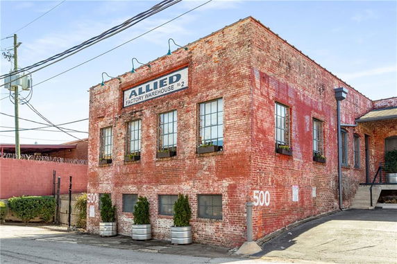 Front view of a brick warehouse building with several windows.