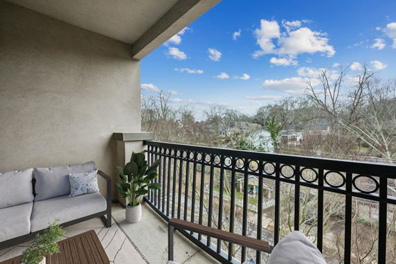View from a balcony overlooking surrounding residential area with trees and houses.