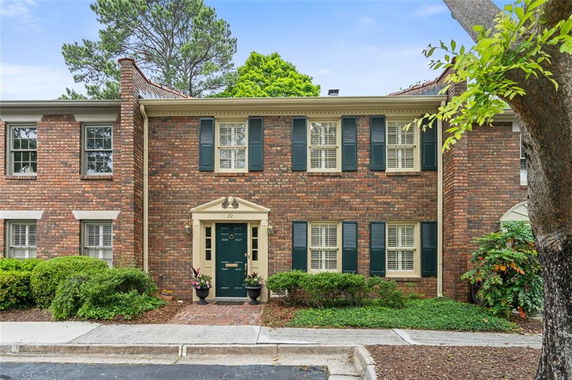 Front view of a two-story brick house with green shutters and door.