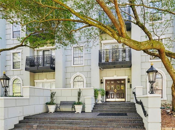 Front view of a multi-story building with balconies and a staircase leading to the entrance.
