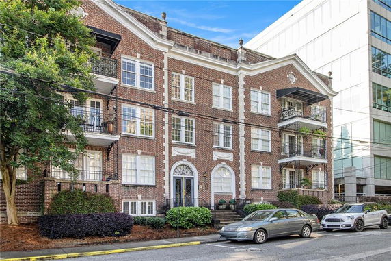 Front view of a multi-story brick apartment building with balconies.