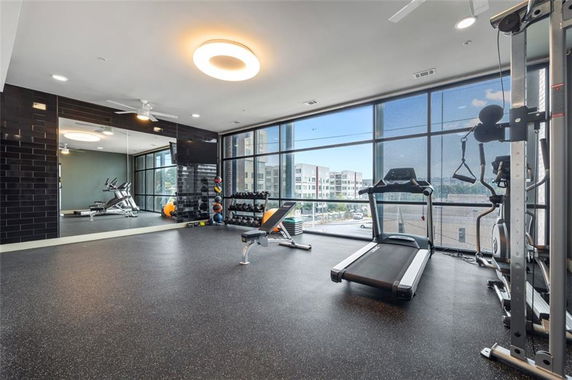 Interior view of a gym area with exercise equipment and large windows.