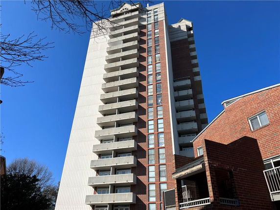 Front view of a tall multi-story residential building with balconies.