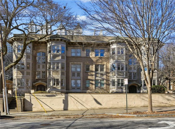 Front view of a multi-story residential building with large windows and bay window designs.