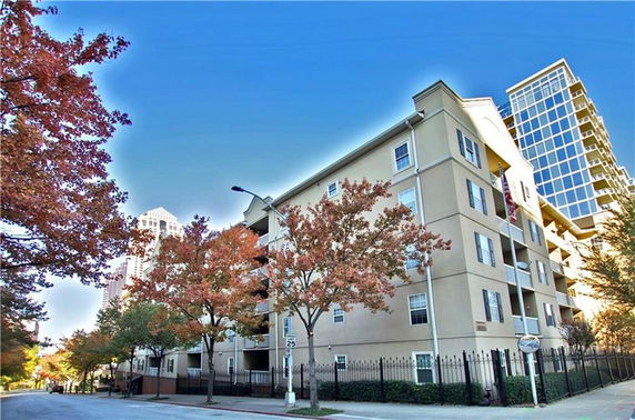 Front view of a multi-story residential building with trees and a street in the foreground.