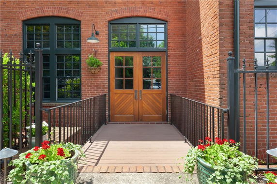 Front view of a red-brick building with a wooden double door entrance and large windows.