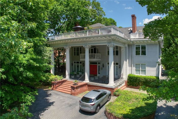 Front view of a two-story house with large columns and a balcony.