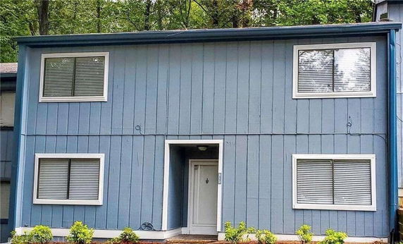 Front view of a two-story blue house with four windows and a white front door.