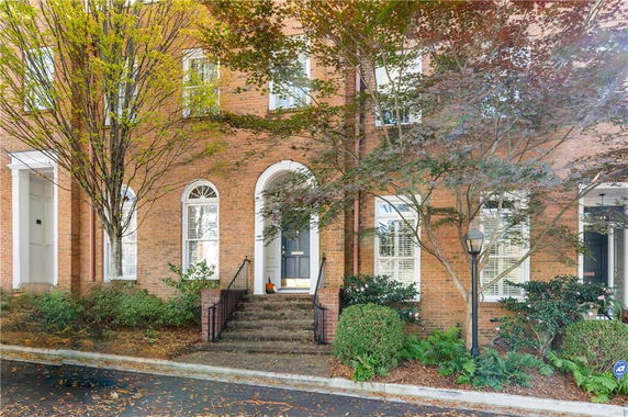 Front view of a multi-story brick townhouse with arched doorway and windows.