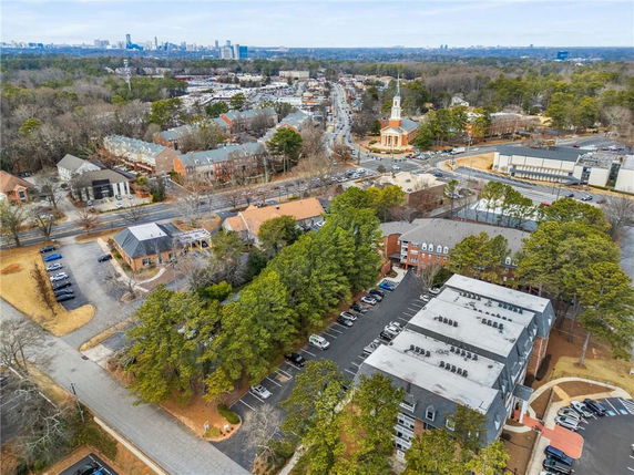 Aerial panoramic view of a suburban area with residential buildings, a large church, and a city skyline in the distance.