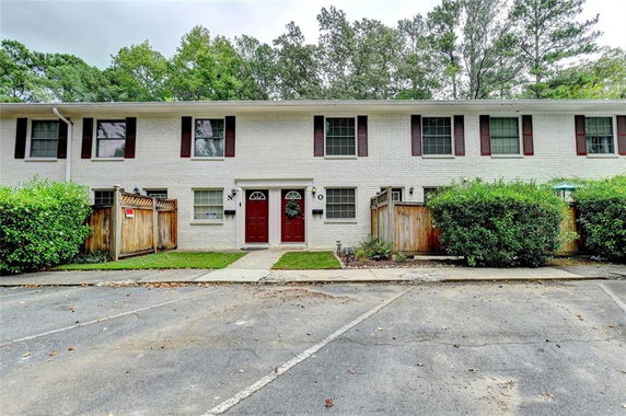Front view of a two-story townhouse with white brick exterior and red shutters.