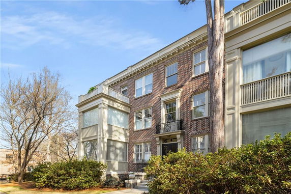 Front view of a multi-story brick building with a balcony.