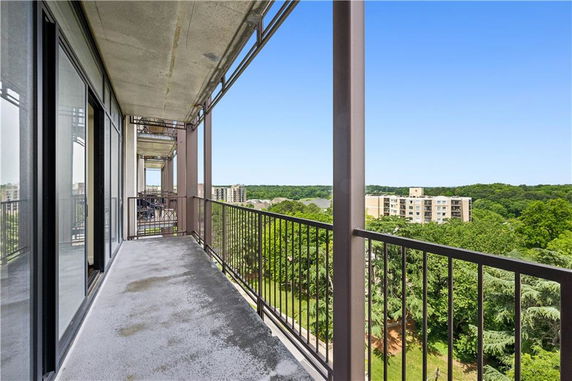 Balcony view of a residential building overlooking trees and other buildings.