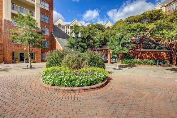 Front view of a multi-story brick building with balconies and a landscaped courtyard.