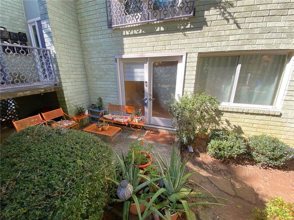 View of a building entrance with a small patio area and plants.