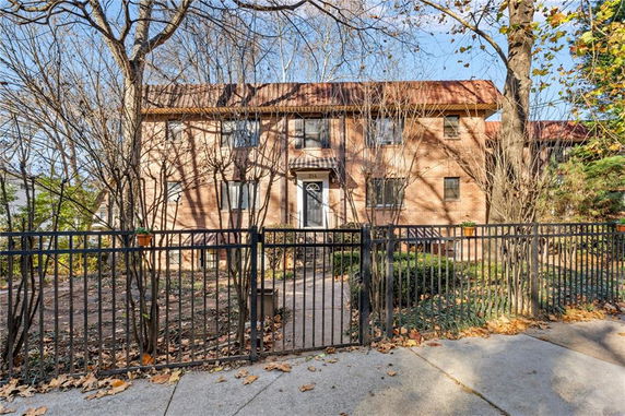Front view of a two-story house with a brick exterior and a gated entrance.