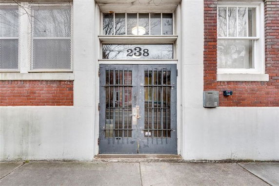 Front view of a building entrance with number 238 and a metal door.