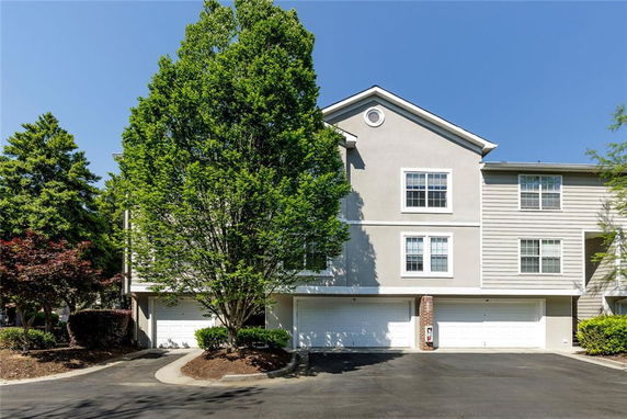 Front view of a multi-story building with garages and a pitched roof.