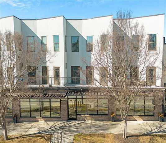 Front view of a multi-story modern building with large windows and a paved walkway.